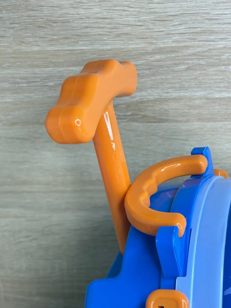 Mango telescópico naranja desplegado de maleta médica infantil azul, mostrando detalle del asa de arrastre de plástico brillante.