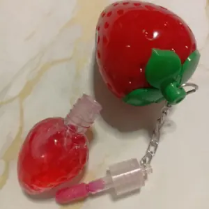 Bálsamo labial hidratante con brillo rojo intenso en frasco con forma de fresa y llavero incluido.