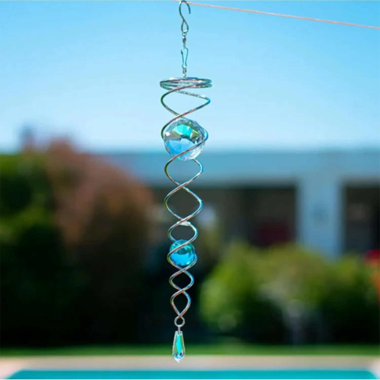 Espiral colgante metálica plateada para jardín con dos esferas de cristal azul y colgante inferior, ideal para exteriores.