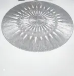 Individual de mesa redondo gris plateado con diseño calado de radios y tramas, hecho en PVC sintético sobre superficie blanca.