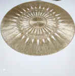 Individual de mesa redondo dorado en PVC sintético con diseño de radios y entramado detallado, sobre superficie blanca.