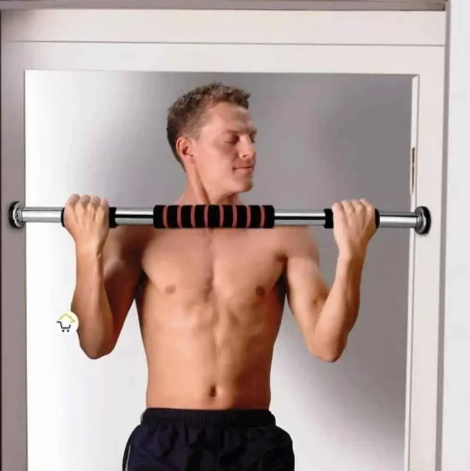 Hombre sin camisa realizando ejercicio de dominadas con barra metálica ajustable instalada en el marco de una puerta, con agarre central antideslizante.