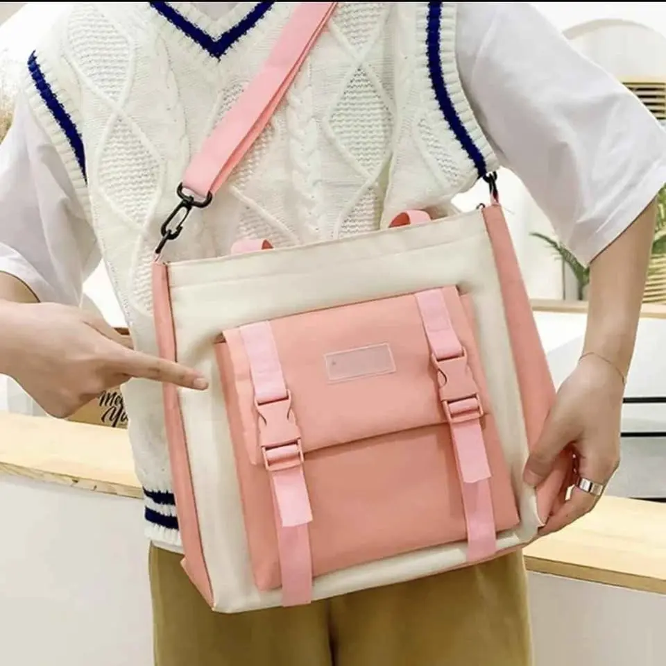 Morral escolar en tonos crema y rosado pastel con correas de ajuste frontal y hebillas, usado cruzado al hombro.