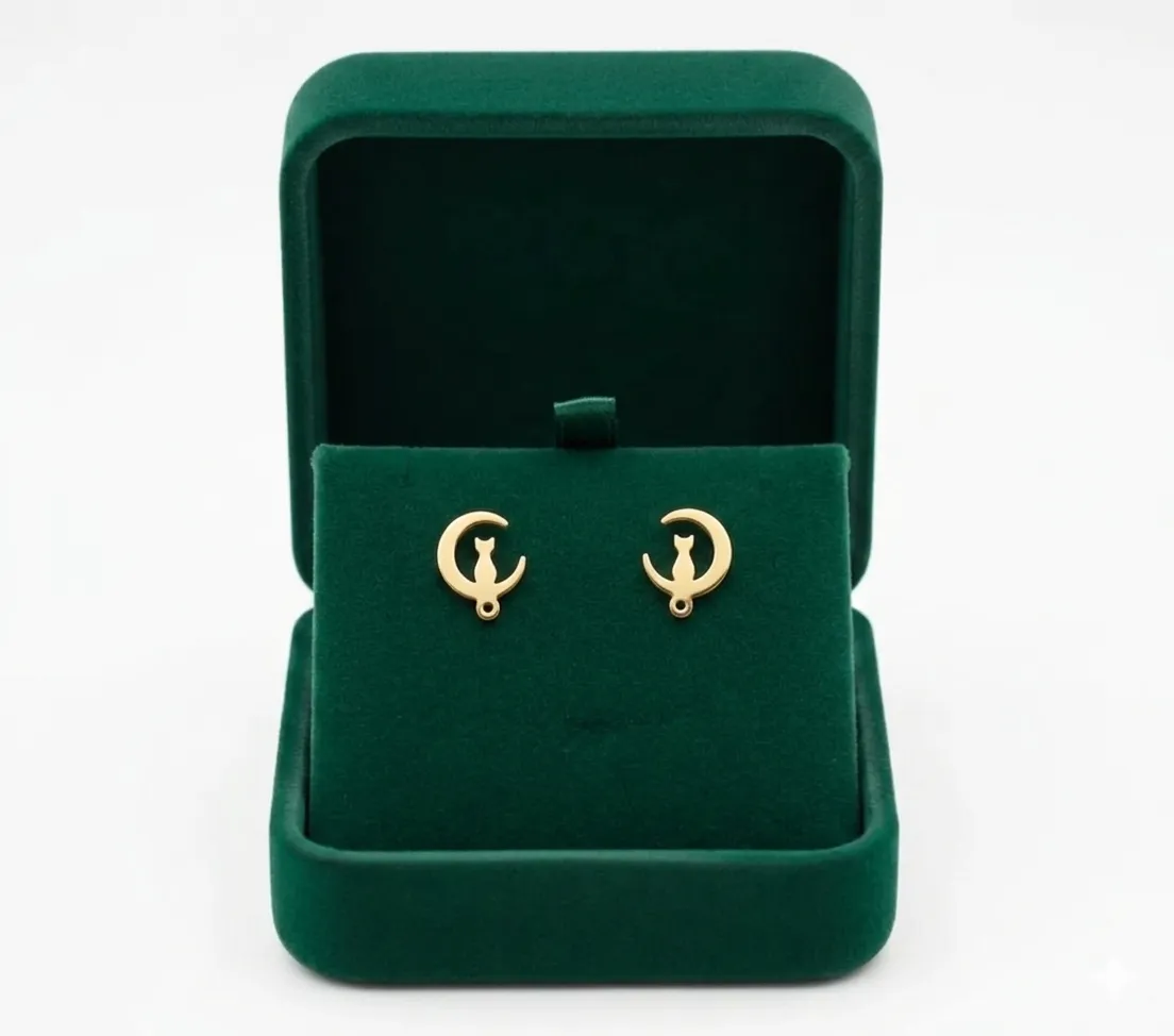 Aretes topitos dorados de acero inoxidable con diseño de gato en luna creciente en un estuche de terciopelo verde.