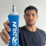 Termo plegable azul GO2RUN de 250ml sostenido por una mano en primer plano, con boquilla transparente para running.