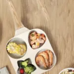 Sartén divisor de aluminio con cuatro compartimentos de formas creativas, acabado crema moteado y mango tipo madera, vista desde arriba.