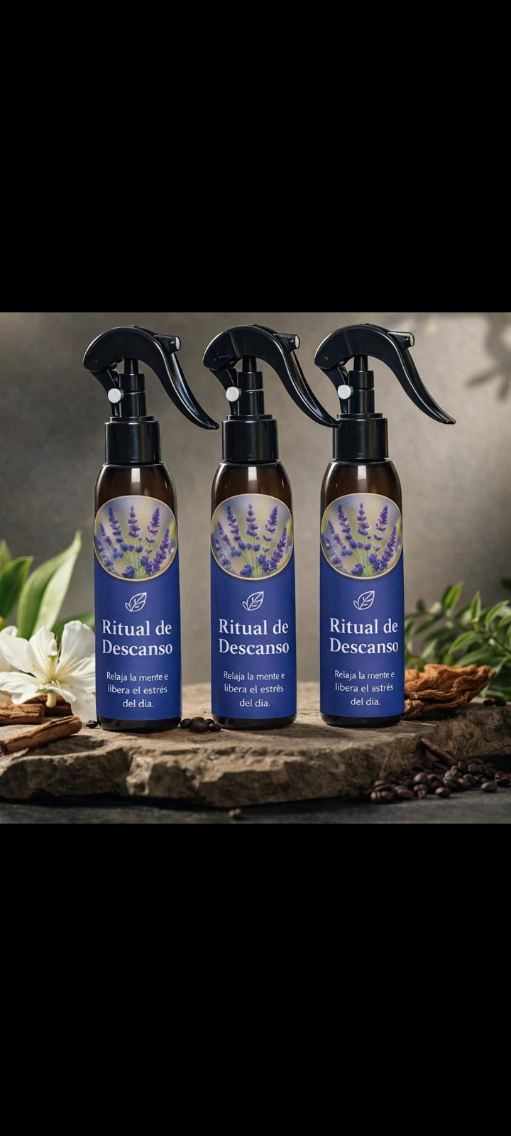 Set de tres atomizadores oscuros con etiqueta azul de lavanda, sobre piedra rústica decorada con flores y hojas.
