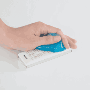 Gel limpiador adhesivo azul moldeable presionando sobre un control remoto blanco para quitar polvo de espacios reducidos.