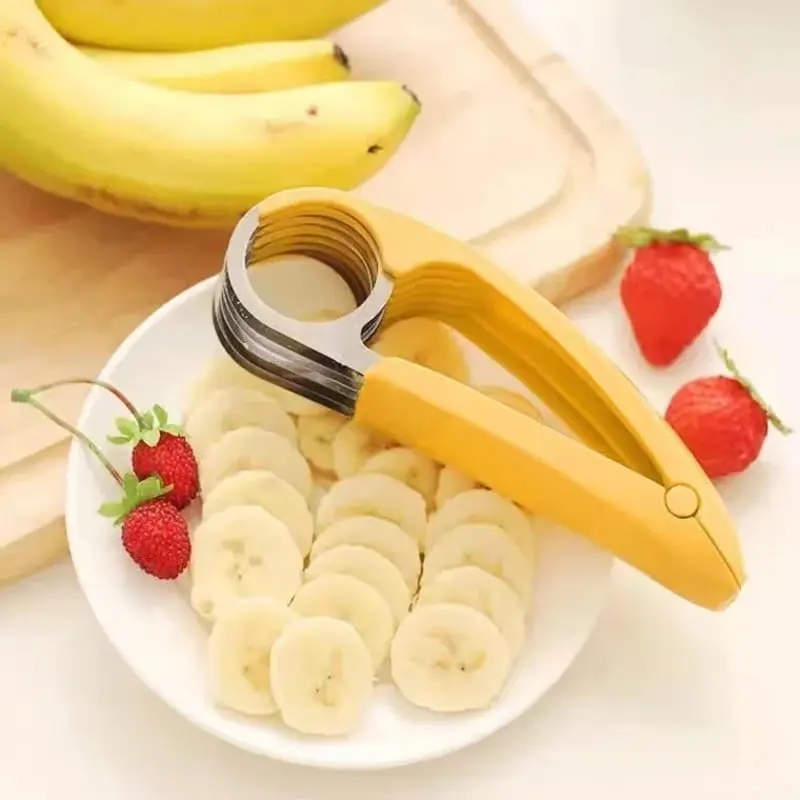 Rebanador de banano con mango amarillo y cuchillas de acero inoxidable, cortando rodajas uniformes sobre un plato blanco con fresas.