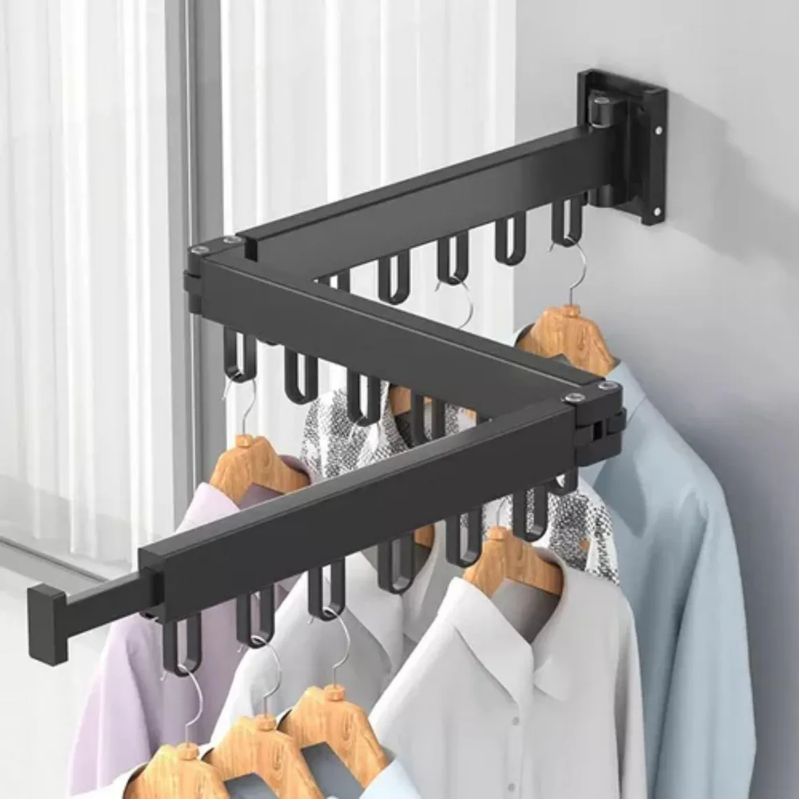 Tendedero extensible de metal negro anclado a la pared, desplegado en zigzag con ganchos para perchas de madera y camisas.