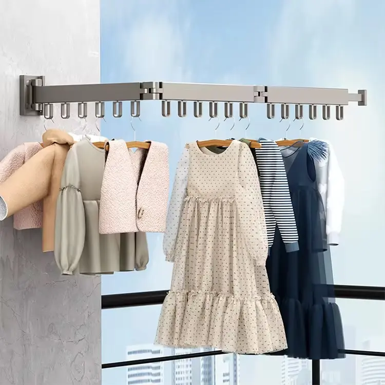Tendedero metálico extensible de pared con múltiples ganchos para perchas, sosteniendo ropa infantil en un balcón con vista urbana.