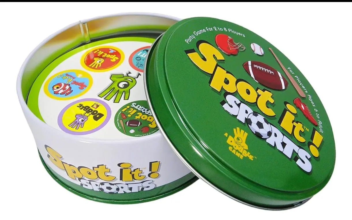 Lata metálica verde abierta de juego de mesa Spot It Sports con cubierta redonda, que muestra el mazo de cartas circulares con iconos deportivos visibles en su interior.