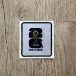 Parche termoadhesivo oficial FIFA World Cup 26 Qualifiers, blanco con bordes negros, número 26 en negro y trofeo central dorado.