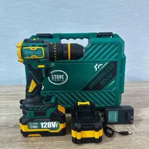 Taladro inalámbrico verde y amarillo con motor brushless, batería de 128VF, estuche, batería de repuesto y cargador sobre superficie de madera.