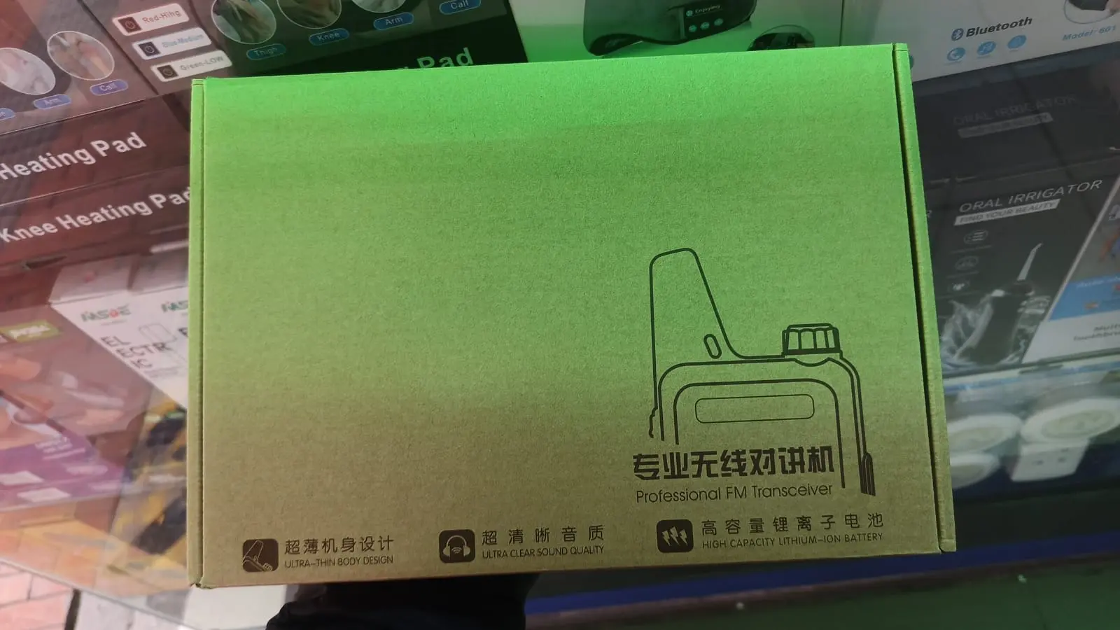 Caja de cartón verde con negra de radio intercomunicador portátil, diseño textuizado y textos en español e inglés.