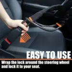 Bloqueador de volante negro con detalles naranjas siendo instalado, sujetando el cable de acero al volante y al asiento del vehículo.