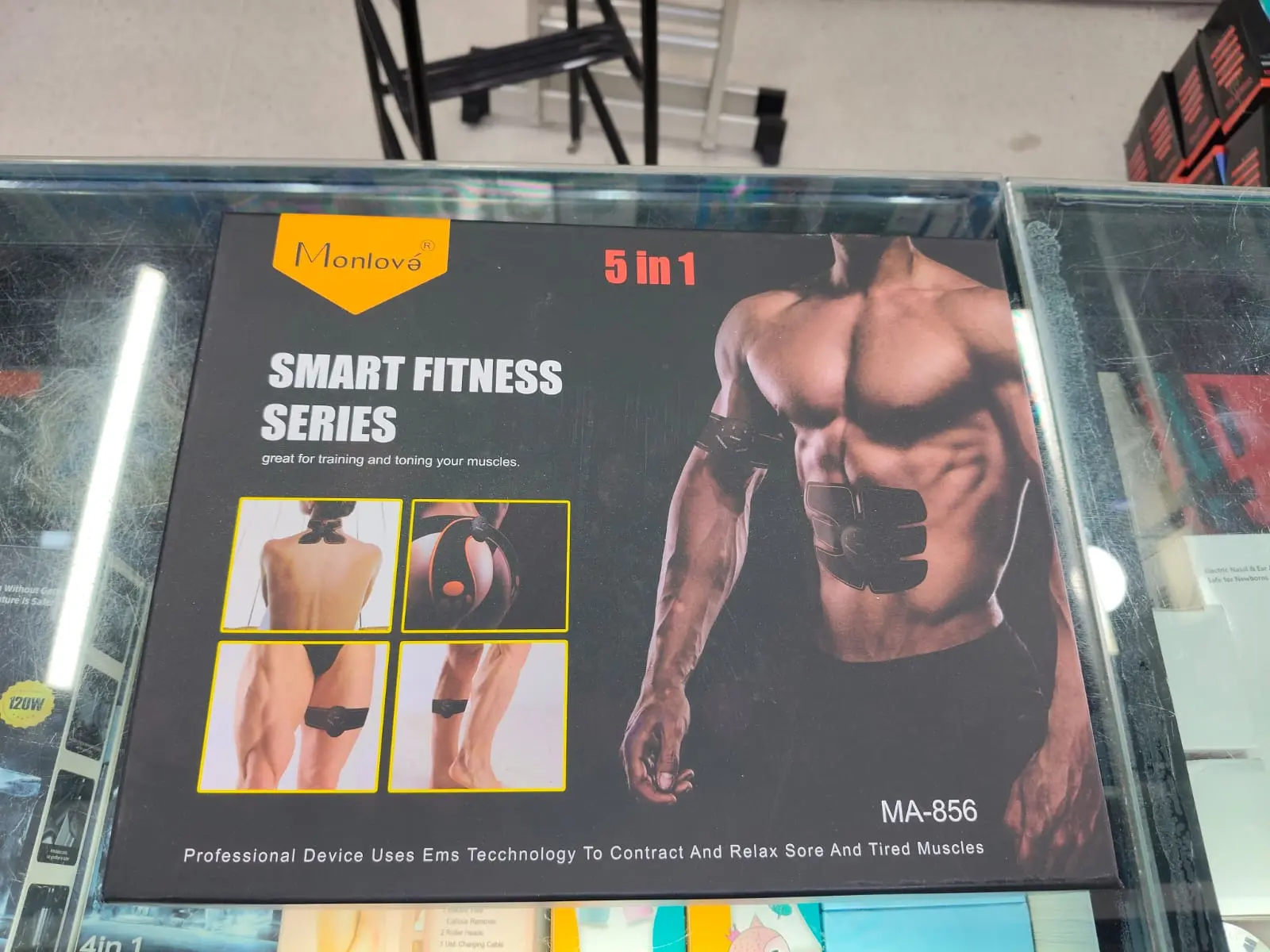 Caja negra de gimnasio EMS 5 en 1 para tonificar músculos, con de un hombre musculoso usando electroestimuladores en el abdomen y brazo.