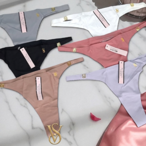 Tangas Victoria's Secret sin costuras en colores gris, blanco, negro, coral, beige y lila con detalles dorados sobre fondo de mármol.