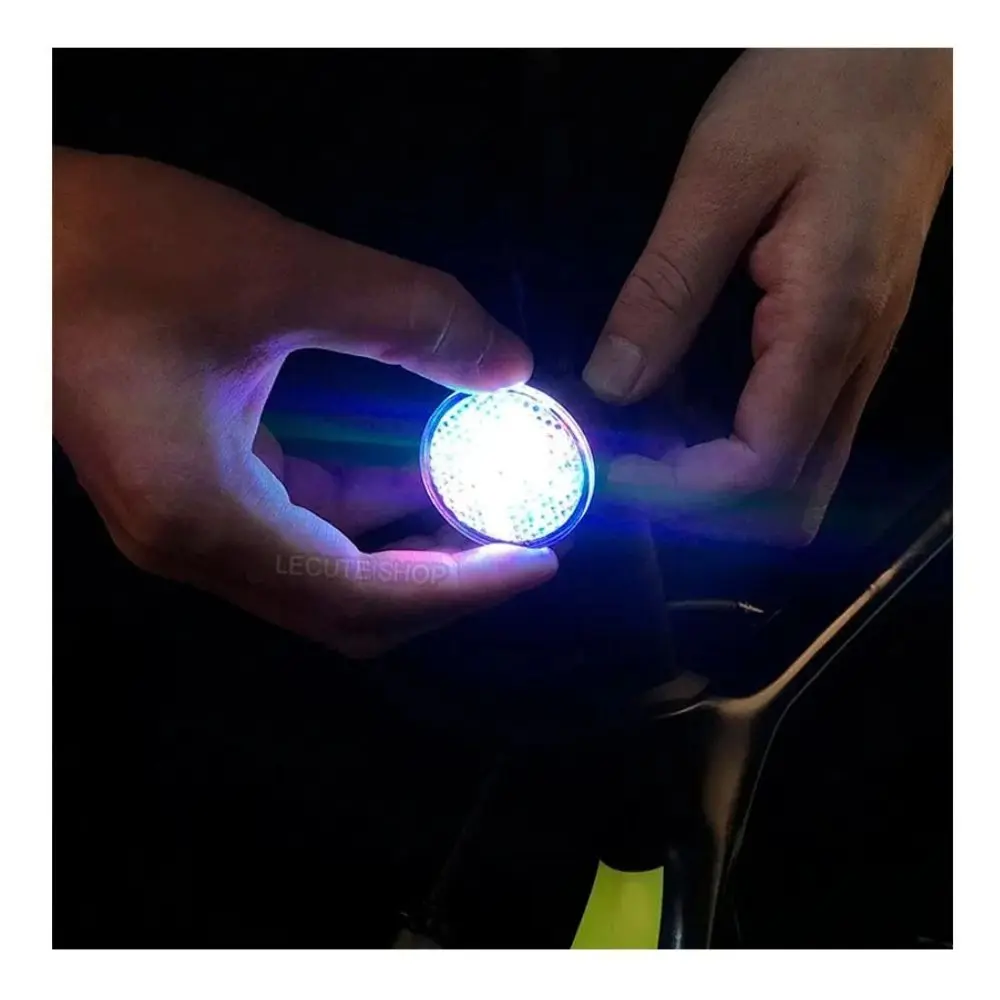 Luz trasera circular para bicicleta con diseño de molino de viento, mostrando su tamaño compacto y brillo intenso entre las manos.