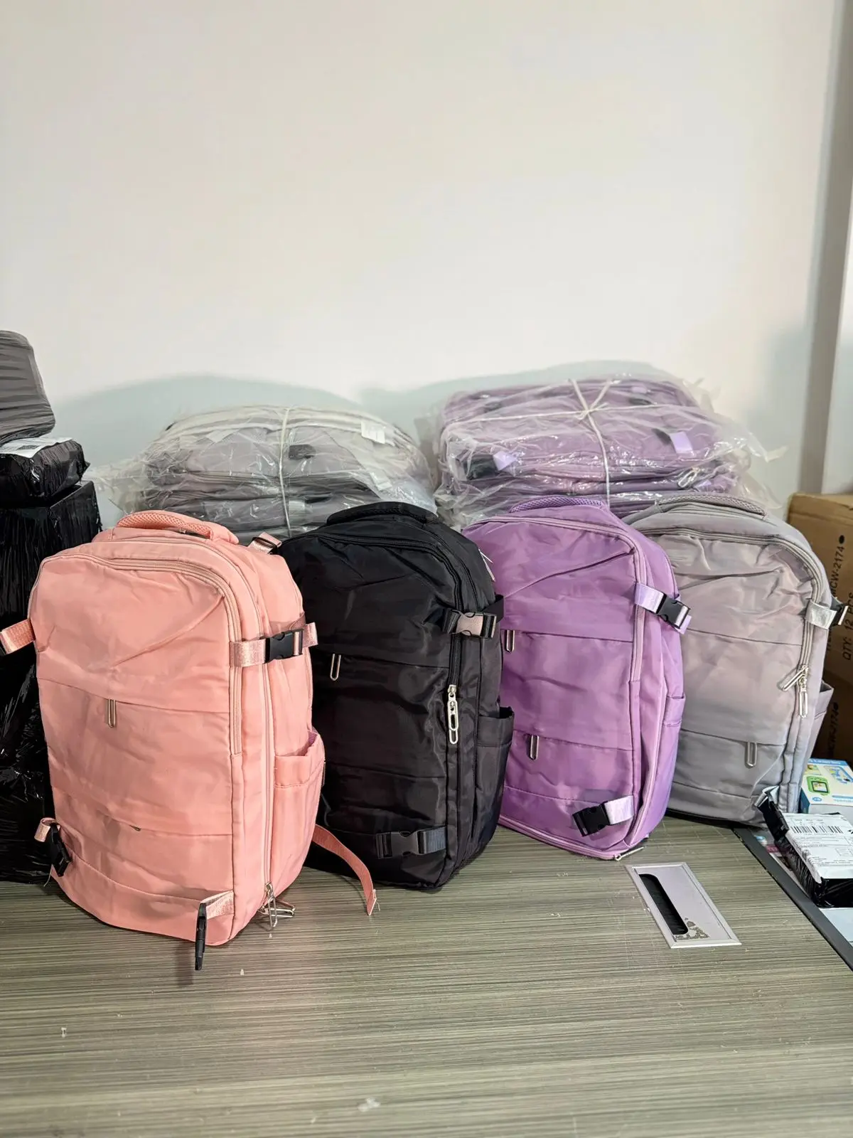 Mochila de viaje impermeable en colores rosado, negro, morado y gris sobre mesa de madera.