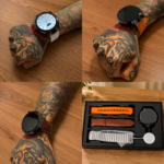 Reloj inteligente con tres correas intercambiables: naranja, cuero marrón y metal plateado, mostrado en muñeca tatuada y en caja de presentación.