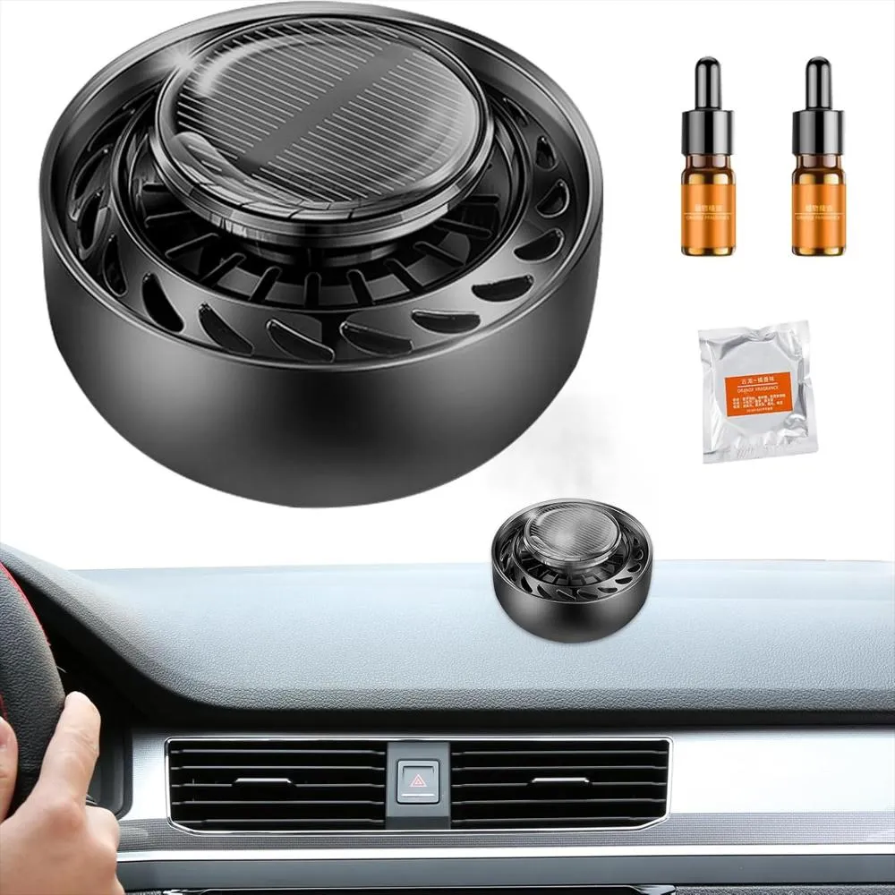 Difusor aromático negro de lujo para carro, con panel solar superior, dos frascos de esencia y repuesto, ubicado sobre el tablero de un vehículo.