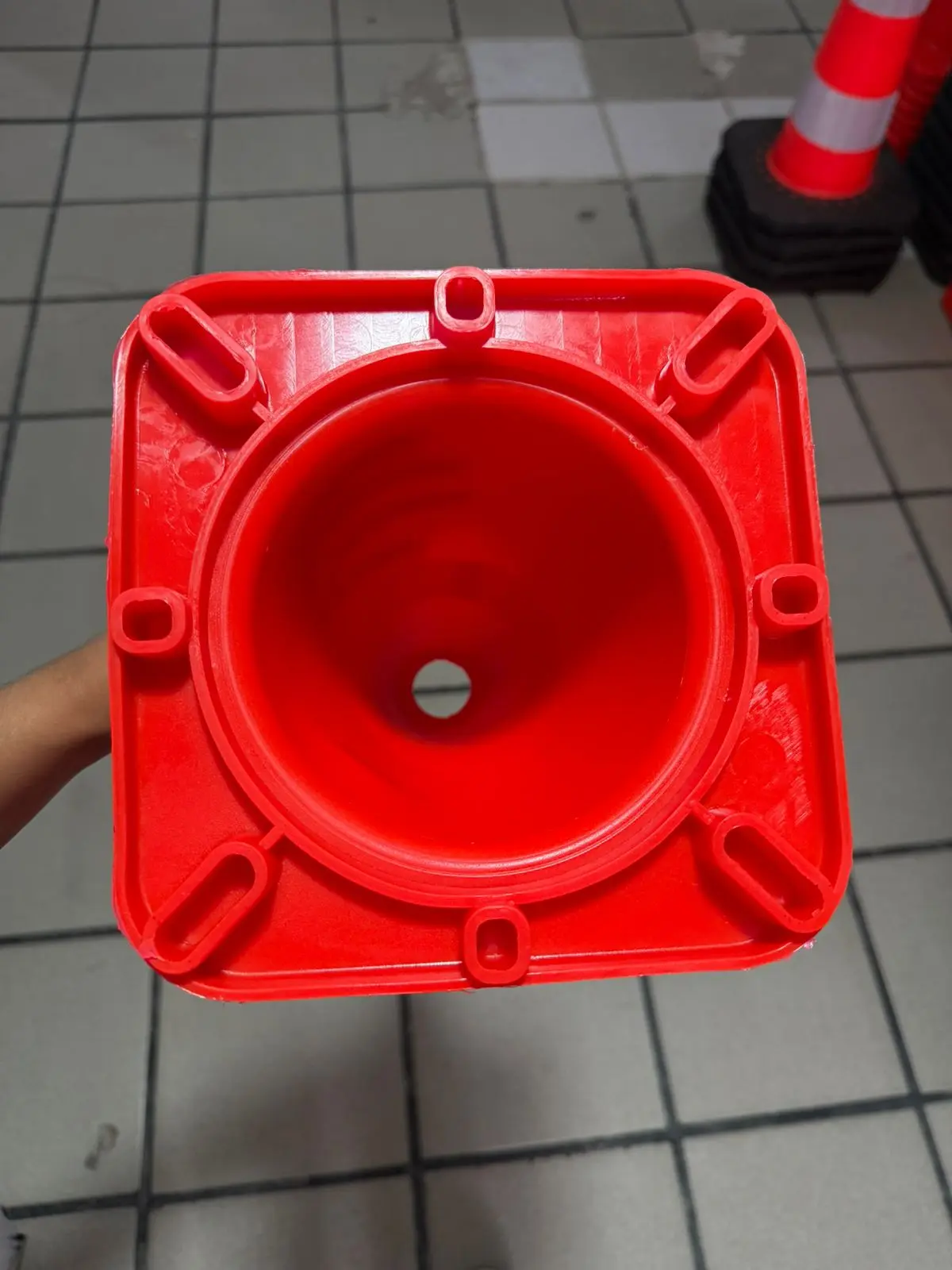 Cono de PVC rojo para señalización vial visto desde la base superior cuadrada, mostrando su interior cónico y diseño estructural resistente.