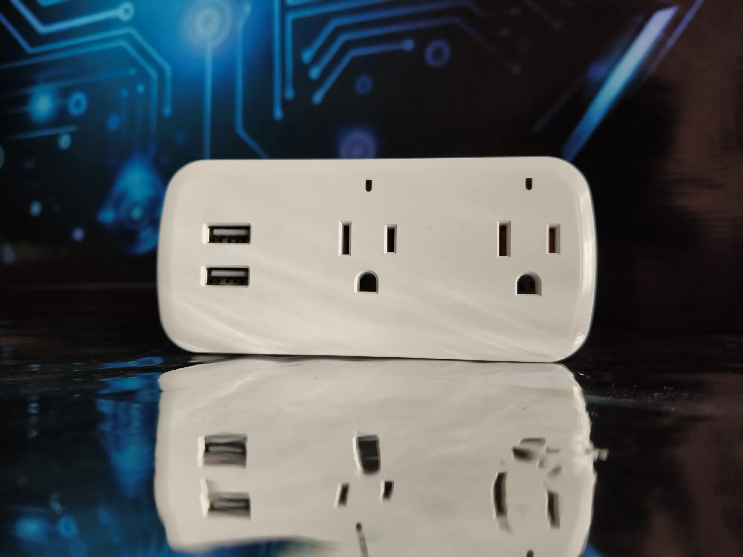 Tomacorriente inteligente blanco con dos tomas y dos puertos USB, sobre superficie reflectante con fondo de circuitos tecnológicos azules.