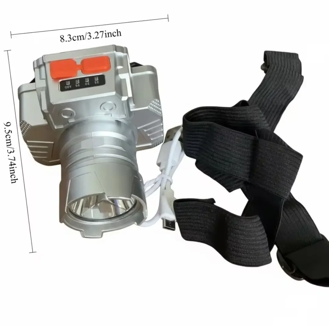 Linterna frontal LED recargable plateada con zoom, correa elástica negra y cable USB, dimensiones de 8.3 cm por 9.5 cm.