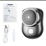 Mini afeitadora eléctrica portátil gris con lámina circular, incluye cable USB, cepillo limpiador y manual de instrucciones.