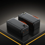 Dos baterías portátiles negras de alta capacidad sobre pedestal, mostrando conectores múltiples, cables integrados, pantalla LED digital y superficie texturizada.