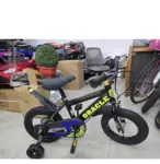 Bicicleta infantil negra Rin 12 con marca ORACLE en amarillo, guardafangos, rueditas auxiliares y marco metálico en tienda.