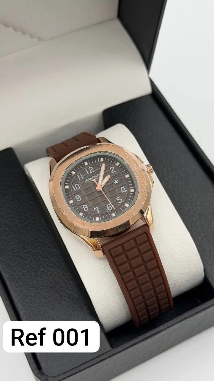 Reloj analógico unisex en caja de oro rosa con esfera marrón, números arábigos y pulso de silicona marrón, presentado en estuche.