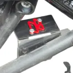 Protector de bomba de freno negra para Hunk 160R con detalle decorativo rojo, instalado sobre el chasis de la motocicleta.
