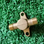 Set x2 conectores de bronce para fumigadora TU26, con rosca macho en ambos extremos y pestañas con orificios de sujeción sobre césped artificial.