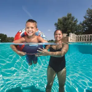 Flotador inflable de Spiderman rojo y azul usado por un niño en una piscina, toma de ángulo dividido entre la superficie y el agua cristalina.