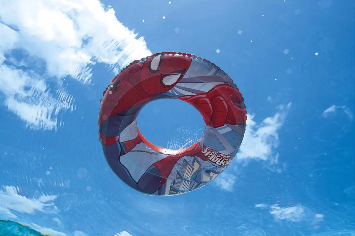 Flotador inflable circular de Spiderman para niños visto desde el agua con diseño rojo y azul de superhéroe bajo cielo despejado
