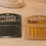 Set de dos estuches de brochas de maquillaje profesional para rostro y ojos, uno negro y otro dorado, sobre superficie de mármol.