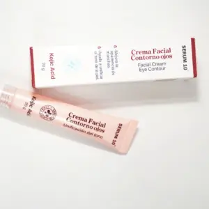 Tubo y caja de crema facial contorno de ojos Serum 10 con ácido kójico, presentación de 20 g, dispuestos sobre fondo blanco.