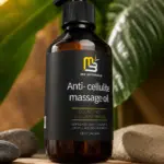 Aceite de masaje corporal M3 Naturals de 240 ml en frasco ámbar con dosificador, sobre base de madera y piedras, rodeado de hojas verdes tropicales.