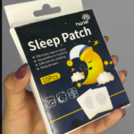 Caja de cartón azul oscuro de parches para dormir con de luna durmiendo y dos parches adhesivos cuadrados con círculo gris.