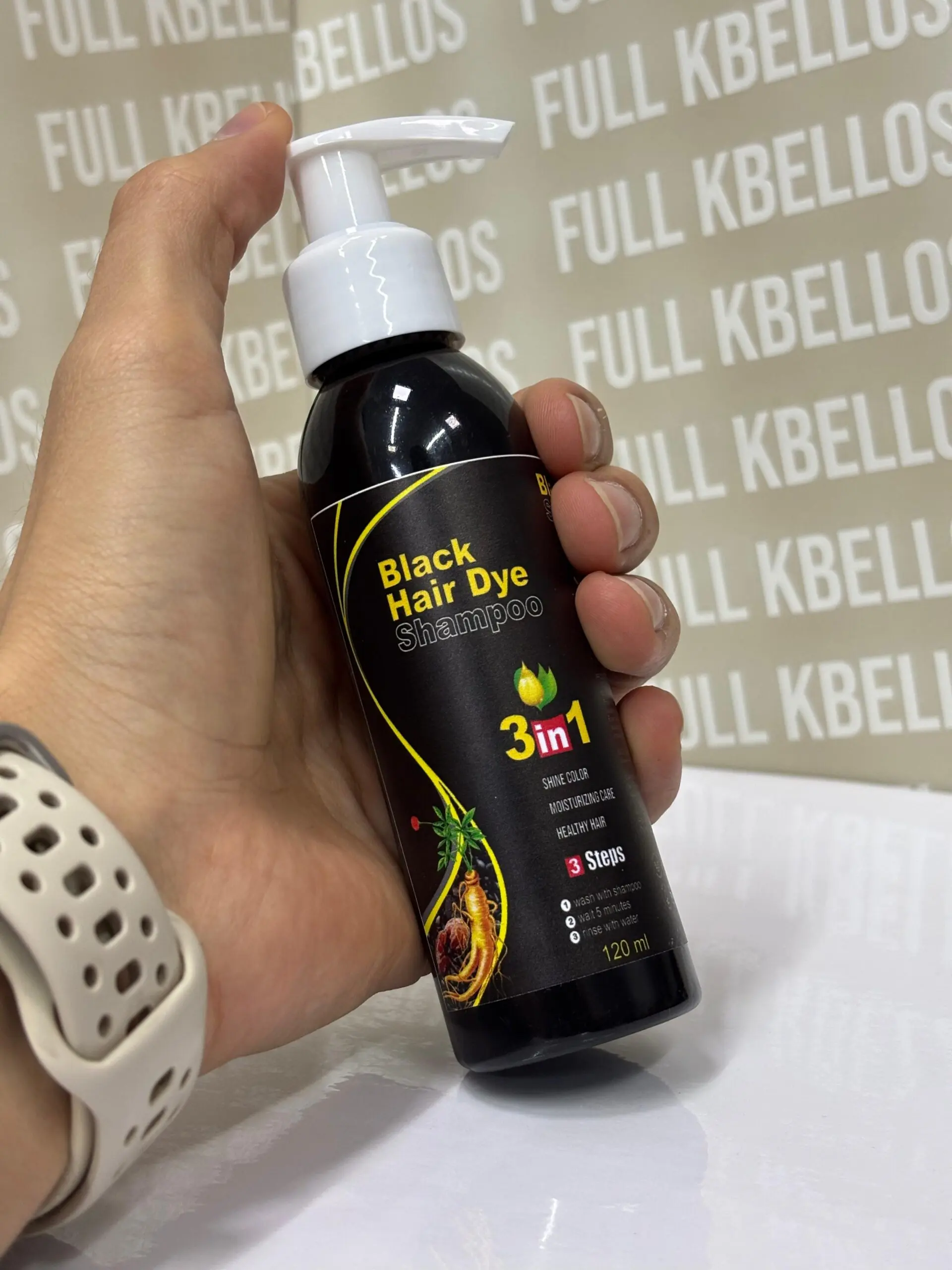 Mano sosteniendo botella negra con dispensador blanco de champú tinte para cabello de 120 ml y diseño de ginseng.