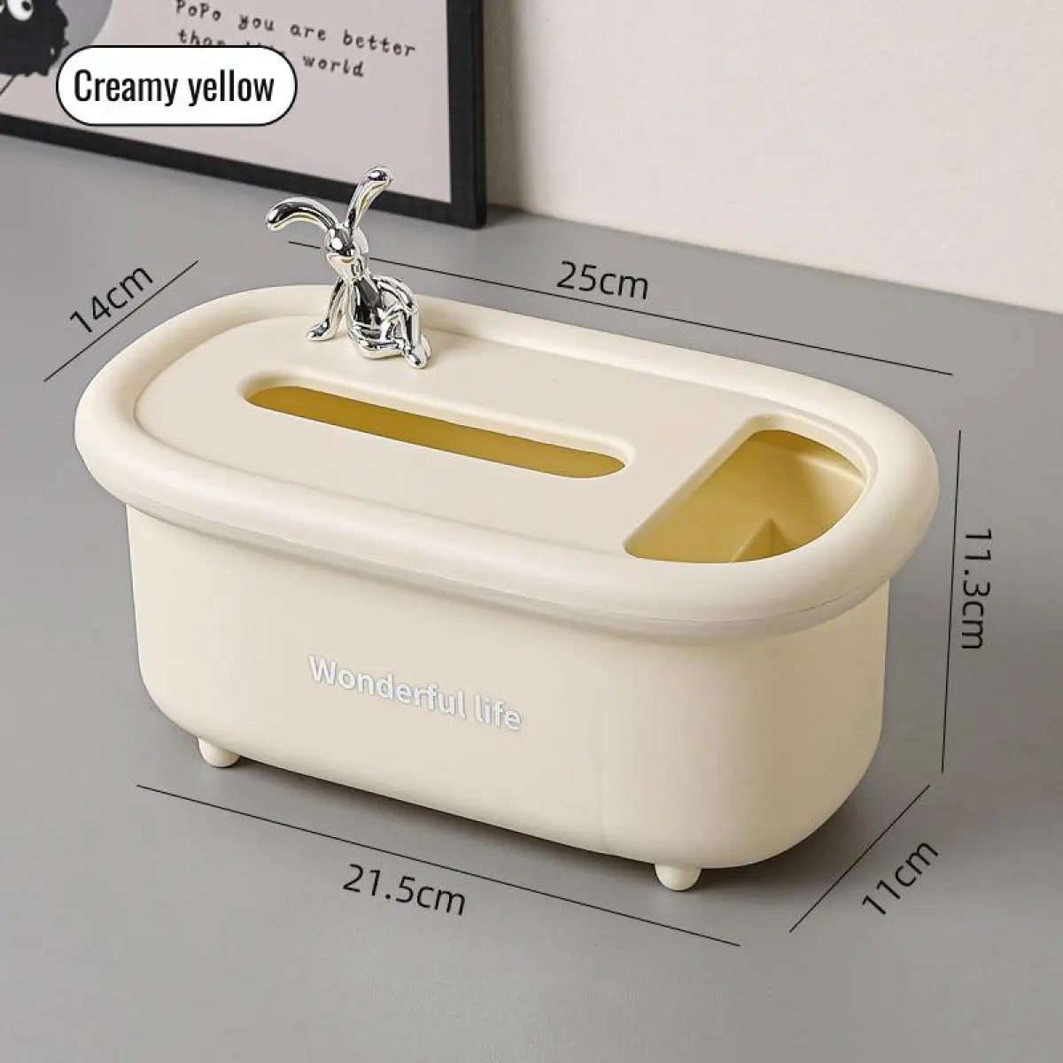 Cajonera organizadora multiusos de polipropileno amarillo crema, dimensiones de 25x14x11.3 cm, con ranura para pañuelos, compartimento auxiliar y figura decorativa plateada en la parte superior.
