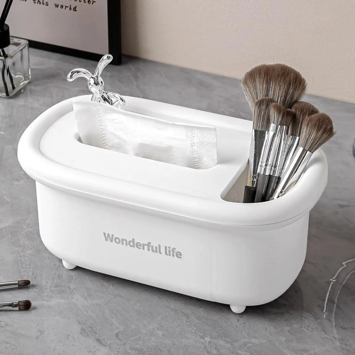 Organizador multiusos blanco de polipropileno con ranura para pañuelos y compartimento para brochas de maquillaje sobre superficie gris.