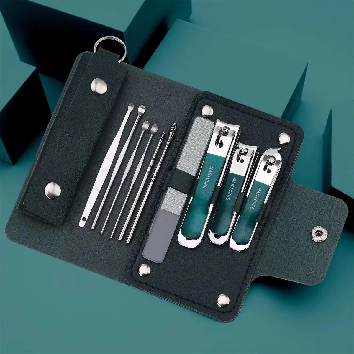 Set de manicura compacto en estuche verde oscuro con cinco herramientas de acero, lima y tres cortauñas turquesa, ideal para viajes.