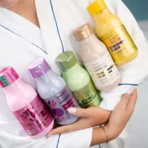 Persona en bata blanca sostiene cinco botellas de finalizador capilar sin enjuague de diferentes colores, incluyendo la variante rosa de cebolla dulce.