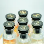 Estuche circular con siete botellas de perfume Louis Vuitton de lujo con atomizador, tapón negro y monograma dorado.