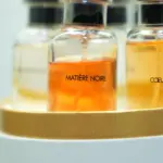 Set de perfumes Louis Vuitton en frascos de vidrio con líquido ámbar, organizados en estuche cilíndrico blanco y dorado