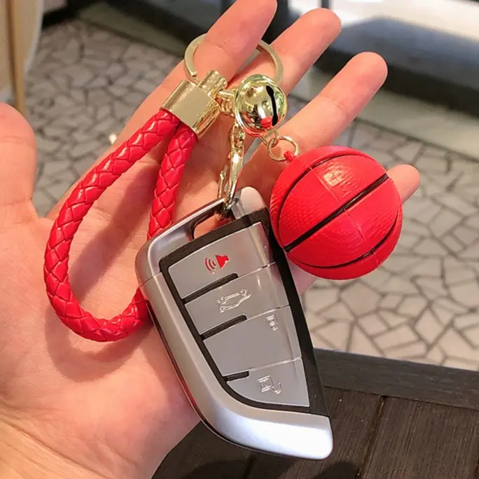 Llavero con correa trenzada roja, balón de baloncesto en miniatura, llavero metálico dorado y funda de llave de carro plateada.