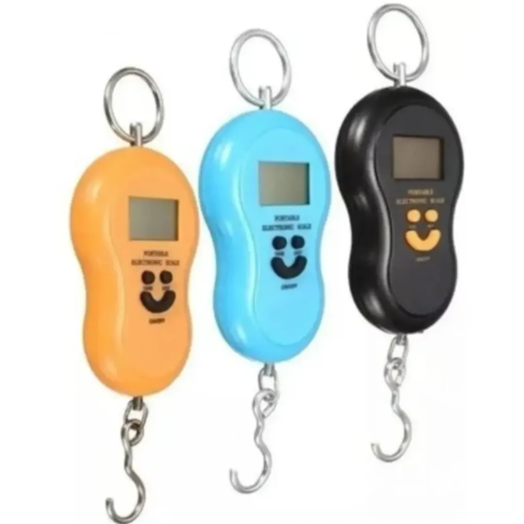 Tres básculas digitales portátiles para equipaje en colores naranja, azul y negro, con gancho metálico, pantalla LCD y diseño ergonómico para pesar maletas.